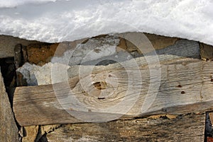 Old wooden planks wall with rusty nails covered with white snow on roof, grunge background texture