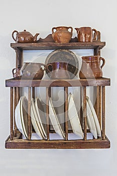 Old wooden plate rack full of pottery