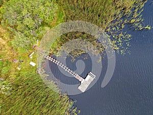 Old wooden platform on calm lakem forest and reed, aerial view photo