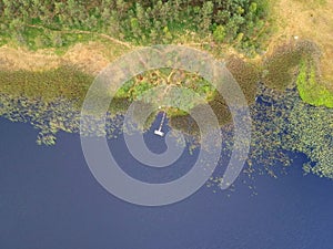 Old wooden platform on calm lakem forest and reed, aerial view photo