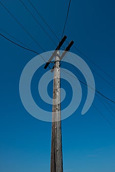 Old wooden pole and wires for communication against the blue sky