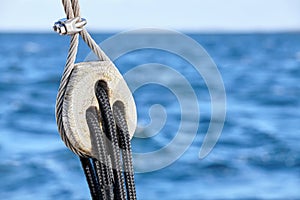 Old wooden pulley block with blue sea in background