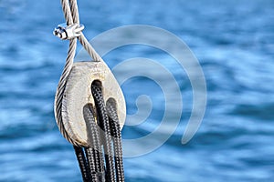 Old wooden pulley block with blue sea in background