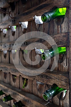 Old wooden pupitre rack for champagne bottles with green empty bottles as decoration in garden