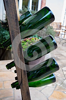 Old wooden pupitre rack for champagne bottles with green empty bottles as decoration in garden