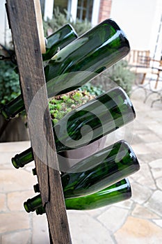 Old wooden pupitre rack for champagne bottles with green empty bottles as decoration in garden