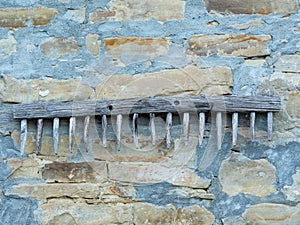 Old wooden rake hanging on a stone wall of a country house