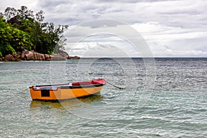 Old wooden red and orange fishing boat anchored at Baie Lazare Public Beach on Mahe Island, Seychelles.