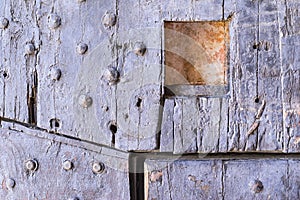 Old wooden riveted gate of fortress with a loophole