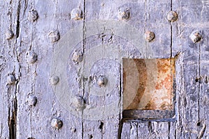 Old wooden riveted gate of fortress with a loophole