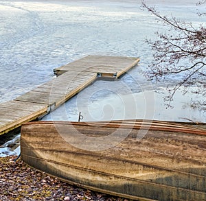 Old wooden rowboat and pier in the frozen lake