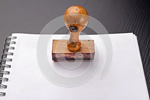 Old wooden rubber stamp on a white piece of notebook. Office accessories on a table