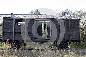 Old wooden ruined boxcar standsing on the rails on the background of blue sky