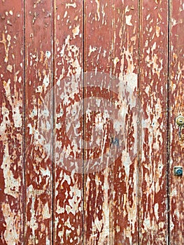 Old wooden rustic door with peeled red paint