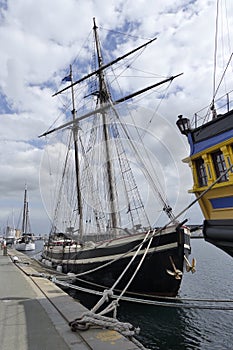 Old wooden sailboats docked in the harbor.