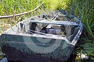 Old wooden shabby dilapidated broken boat for swimming on the banks of the river, lake, sea in the grass and reeds in nature