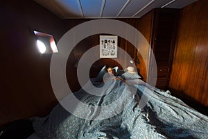 Old wooden ship cabin interor, sleeping woman in bed