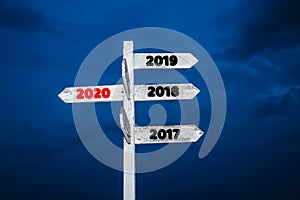 Old wooden sign are arrowheads pointing to new year 2020,with beautiful twilight sky background,with new year`s Eve 2019,concept