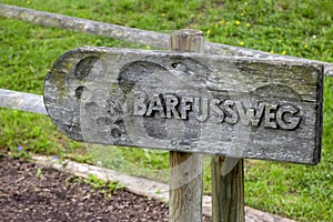 Old wooden sign with the German text Barfussweg