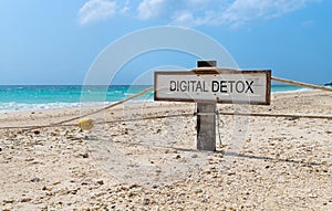 Old wooden sign with text digital detox on tropical beach photo