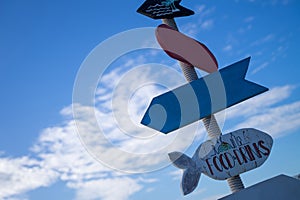 Old wooden signpost on the beach. Bright sky background, happy summer vacation concept