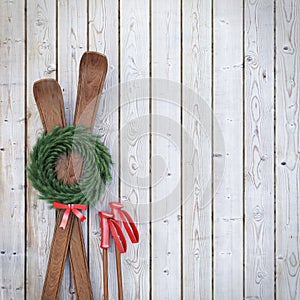 Old wooden skis on wooden planks wall with garland and red ribbon, winter background