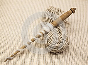 Old wooden spindle with a ball of wool thread for the manufacture of woolen threads on a tissue background