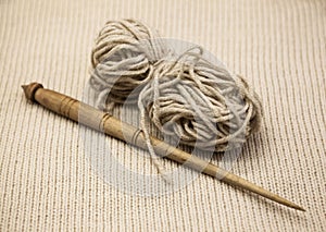 Old wooden spindle with a ball of wool thread for the manufacture of woolen threads on a tissue background