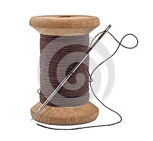 Old wooden spool of thread and needle on a white background. Sewing accessories