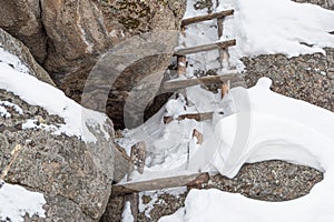 Old wooden staircase on snow covered cliff face