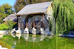 An old wooden, stone, village house in a above a small lake, the river is reflected in water. Rural landscape in Uman, Ukraine