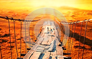 Old wooden suspension bridge with rusty cables and rotten planks. Selective focus.