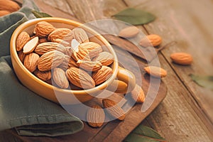 Old wooden table adorned with almonds nestled in an orange cup