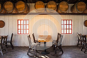 Old wooden table and chairs locate in restaurant with wooden wine barrel interior in restaurant.