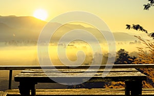 Old wooden table at the coffee shop blurred background  The sun's rays through at the top of the hill and the moving fog