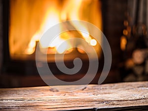 Old wooden table and fireplace with warm fire on the background