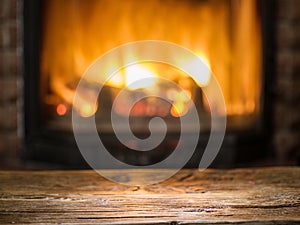 Old wooden table and fireplace with warm fire.