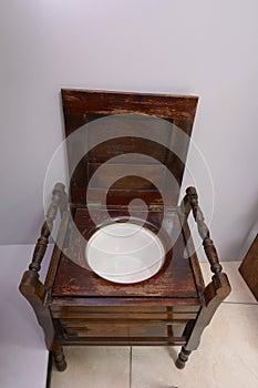 An old wooden toilet bowl, designed like chair