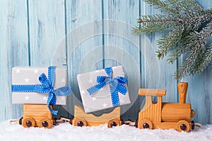 Old wooden toy train with Christmas gifts, wooden background