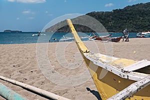 An old wooden traditional banca or outrigger boat lying in the sand dragged inland by the owner. At Calayo beach, Nasugbu,