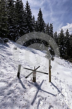 Old wooden turnstile in the snowy hillside by the forest