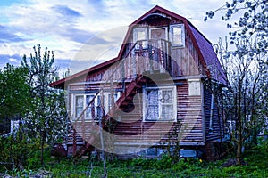 Old wooden two-storey abandoned burgundy-colored country house