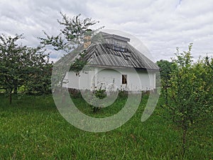 An old wooden Ukrainian hut on a farm in the evening, cloudy sky