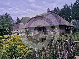 An old wooden Ukrainian hut on a farm in the evening, cloudy sky