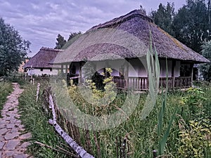 An old wooden Ukrainian hut on a farm in the evening, cloudy sky