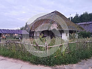 An old wooden Ukrainian hut on a farm in the evening, cloudy sky