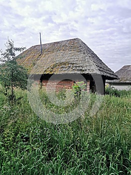 An old wooden Ukrainian hut on a farm in the evening, cloudy sky