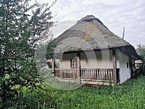 An old wooden Ukrainian hut on a farm in the evening, cloudy sky