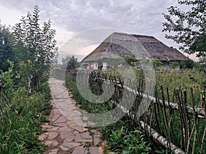 An old wooden Ukrainian hut on a farm in the evening, cloudy sky