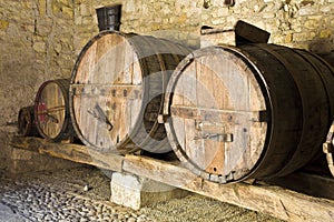 Old wooden vine barrels in an old italian cellar with stone floor and walls